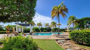 A pool area with palm trees, a pergola, and a stone pathway.