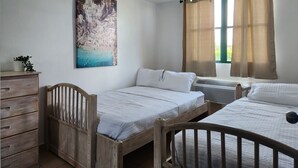 A bedroom with two wooden beds, a wooden dresser, a radiator, and a painting on the wall.