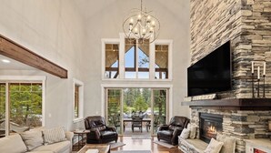A spacious living room with a stone fireplace, leather sofas, and a large TV. - Luxury Suncadia Retreat- Golf Course View, Fire Pit, Pool Table, Family-Friendly (Cle Elum)
