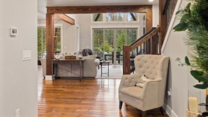 A spacious living area with a wooden floor, a dining table, and a comfortable armchair. - Luxury Suncadia Retreat- Golf Course View, Fire Pit, Pool Table, Family-Friendly (Cle Elum)