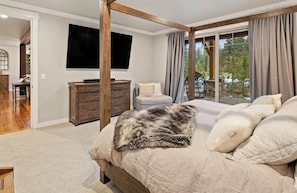 Une chambre dotée d’un grand lit, d’une commode en bois, d’un téléviseur à écran plat et offrant une vue sur l’extérieur grâce à de grandes fenêtres.