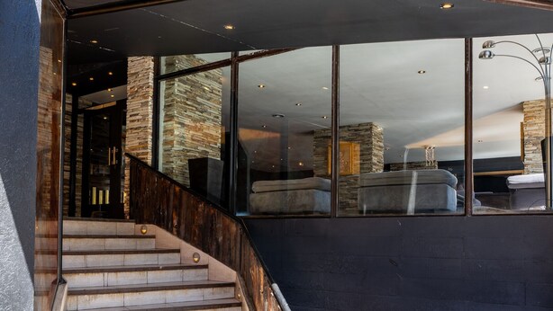 A modern staircase leading to a covered outdoor area with stone walls and a wooden deck. - Park Bariloche (San Carlos de Bariloche)