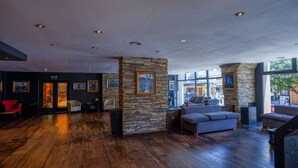 A spacious lobby with wooden flooring, stone accents, and modern furniture. - Park Bariloche (San Carlos de Bariloche)