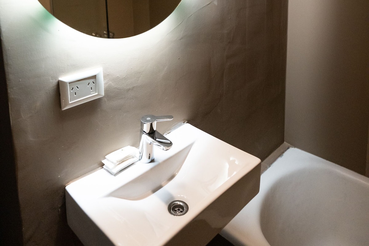A bathroom with a round mirror, a sink, and a bathtub.