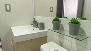 Een bad/douchecombinatie, handdoeken, zeep, toiletpapier