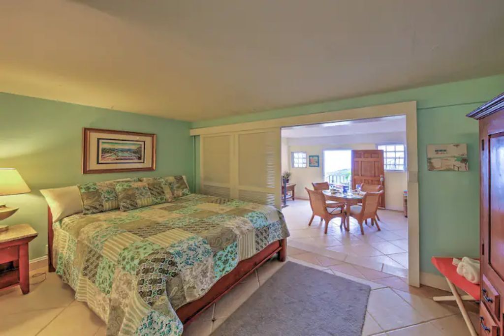 A bedroom with a bed, bedside table, and a painting on the wall.