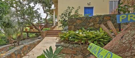 A stone pathway leading to a house with a blue door and a sign reading "Villa Van Duke".