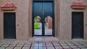 A building entrance with a large black door, two smaller doors on either side, and a tiled floor. - Casa Del Senator Marrakech (Aghouatim)