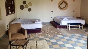 A room with two beds, a chair, a small table, and decorative wall art. - Casa Del Senator Marrakech (Aghouatim)