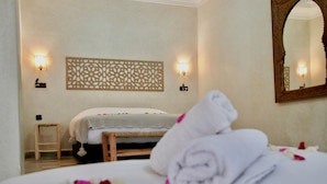 A hotel room with a bed, a wooden stool, and a decorative wall panel. - Casa Del Senator Marrakech (Aghouatim)