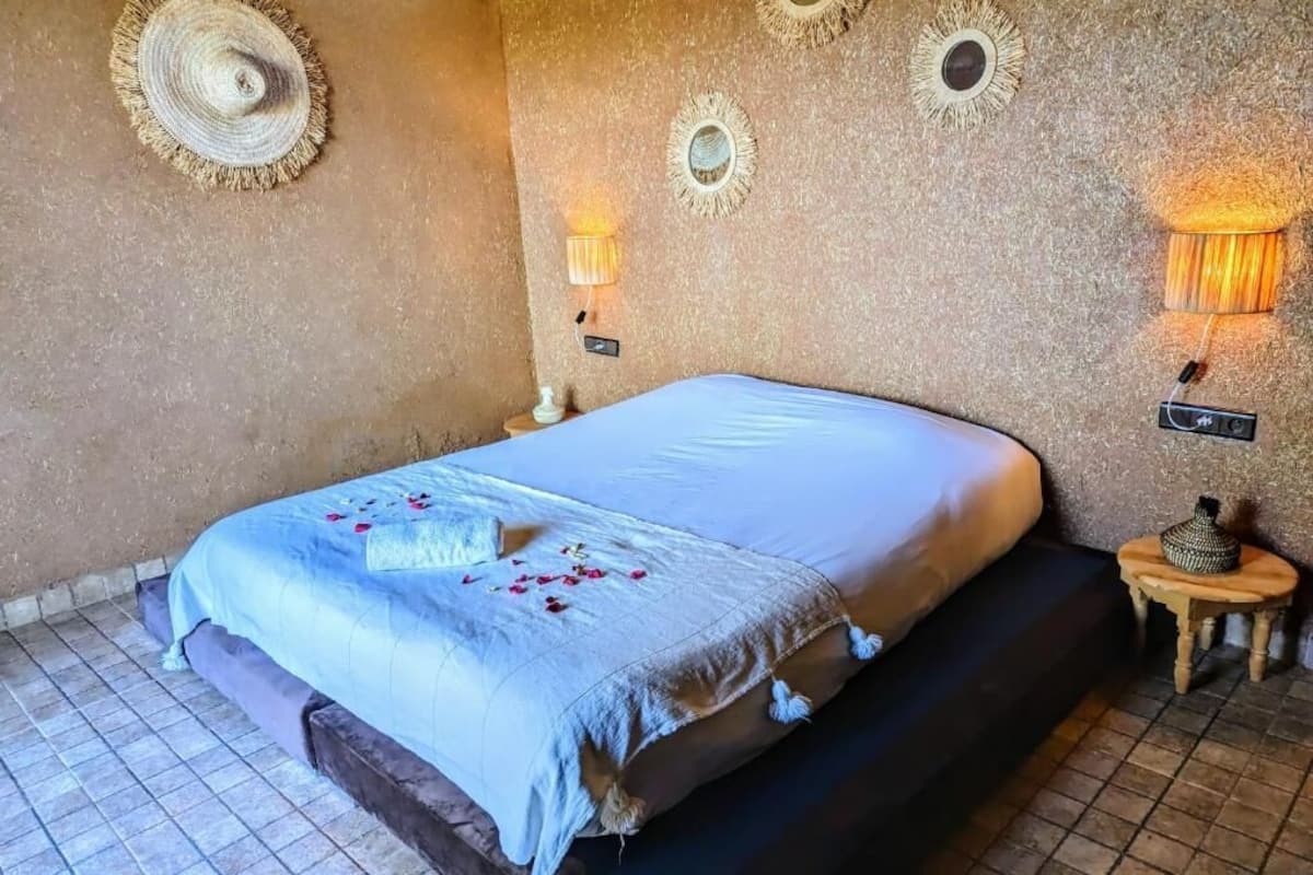 A bedroom with a bed, a nightstand, and decorative wall sconces.