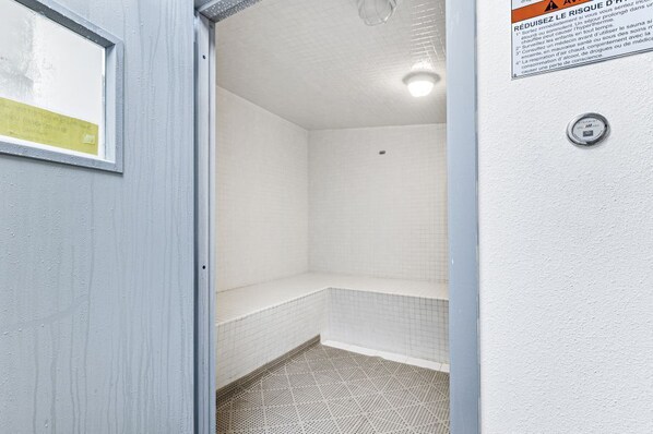 A small, enclosed shower area with tiled walls and floor, a bench, and a visible water control knob.