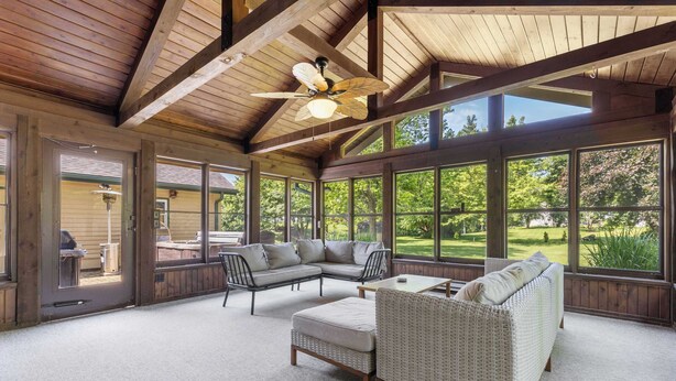 A spacious room with a large window, a ceiling fan, and a sectional sofa. - Golfer's Retreat *hot tub* *arcade* *spa* (Rockford)