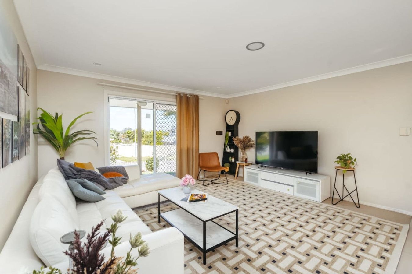A living room with a sofa, coffee table, TV, and a plant.