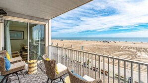 Un balcon meublé de mobilier en osier donnant sur une plage.
