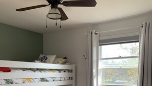 A bunk bed room with a ceiling fan, a window with curtains, a bookshelf, and a radiator. - Cozy open concept home, walking distance to Canada Games grounds (Charlottetown)