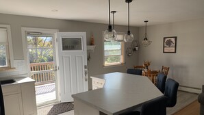 A modern kitchen with a large island, pendant lights, and a dining area with wooden chairs and a table. - Cozy open concept home, walking distance to Canada Games grounds (Charlottetown)