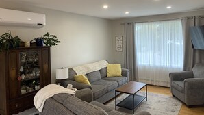 A living room with a grey sofa, a wooden coffee table, and a cabinet with glass doors. - Cozy open concept home, walking distance to Canada Games grounds (Charlottetown)