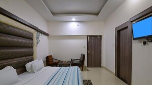 Hotelkamer met een groot bed, een aan de muur bevestigde televisie, een bureau met stoel en een deur.