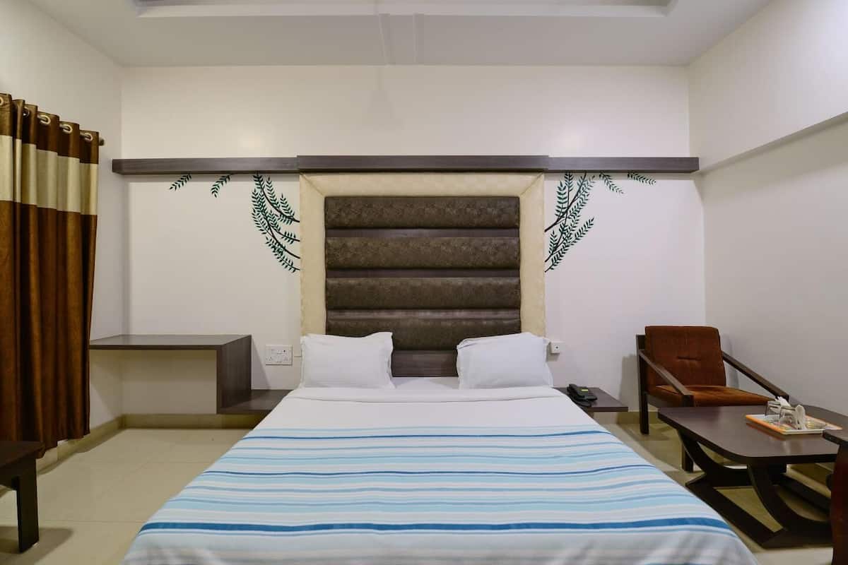 Een hotelkamer met een bed, een bureau, een stoel en een klein tafeltje.
