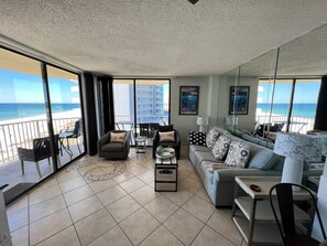 Relax in a spacious living area with a large balcony overlooking the ocean, featuring a sofa, coffee table, and armchair.
