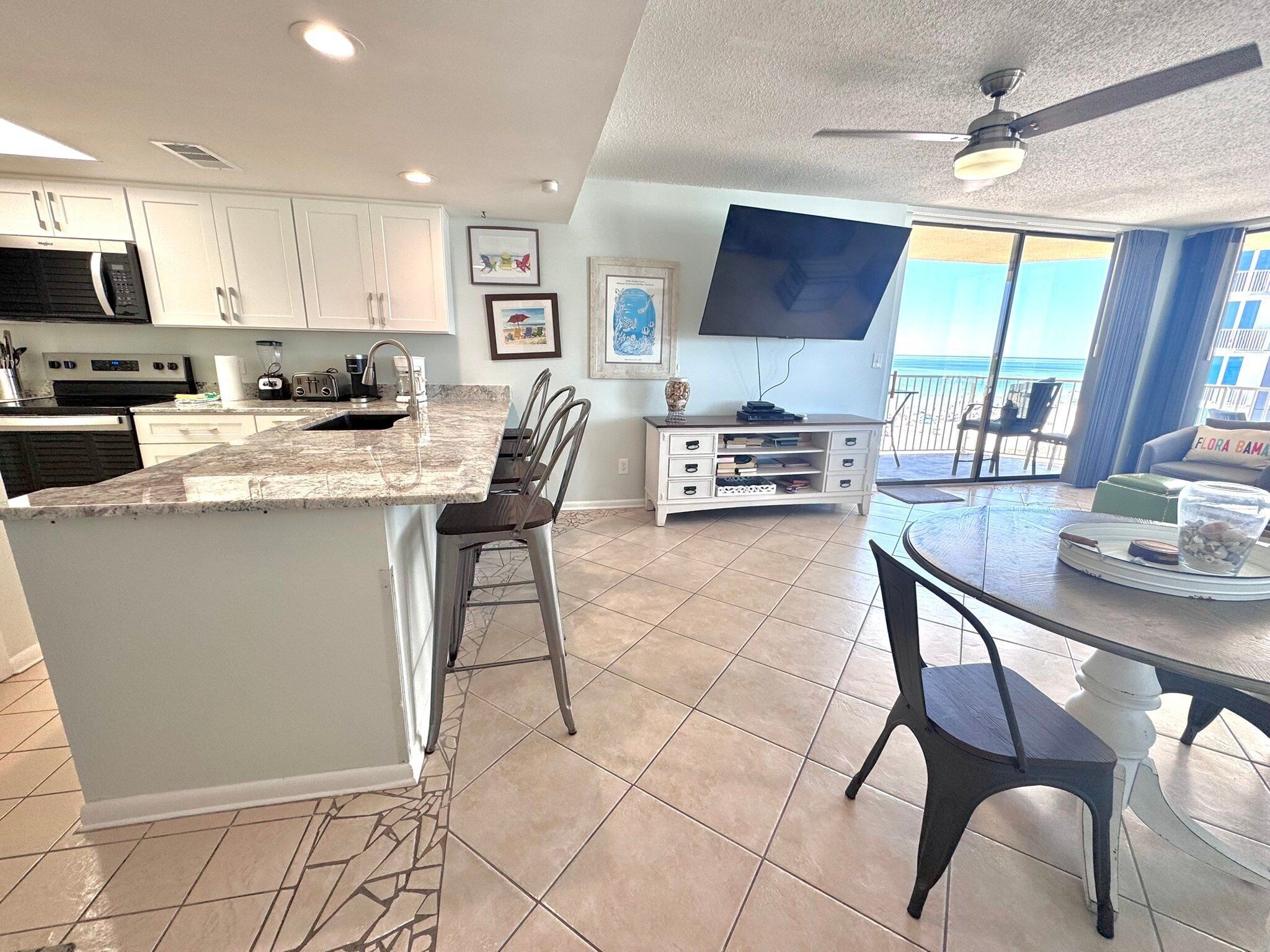 A modern kitchen with white cabinets, a granite countertop, and a dining area with a round table and chairs.