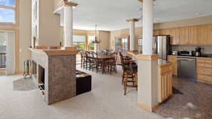 A spacious kitchen with a central island, wooden cabinets, and a dining area with chairs. - Summit View Townhouse 1mi to Mt Snow w/ Fireplace! (Dover)
