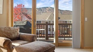 A room with a sliding glass door leading to a deck with a view of a mountain and autumn foliage. - Summit View Townhouse 1mi to Mt Snow w/ Fireplace! (Dover)