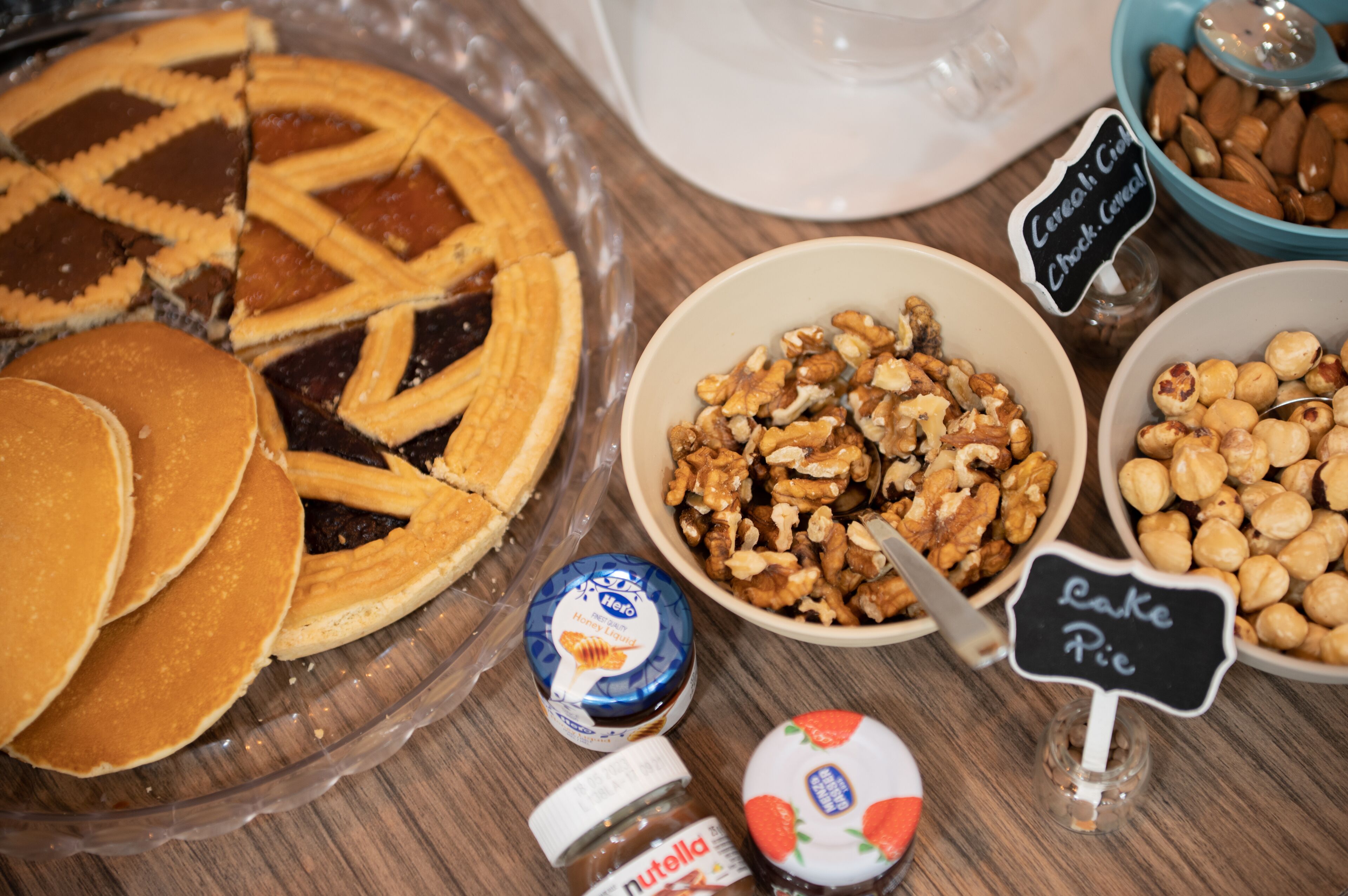 A breakfast buffet with a pie, pancakes, and various spreads like Nutella and honey.