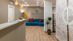 Et receptionsområde med en blå sofa, et træreceptionistskab og en væg med et 'NEOCORE' skilt.