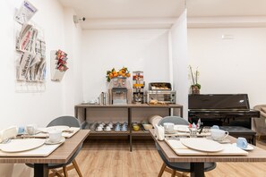 A dining area with a piano, a coffee machine, and neatly arranged tableware. - Neocore  (Naples)