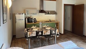 A compact kitchen with a wooden ceiling, a refrigerator, a microwave, a coffee maker, and a sink.