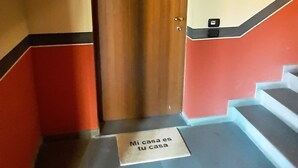 A staircase with a wooden door at the top, a sign on the floor, and a wall with a red and beige color scheme.