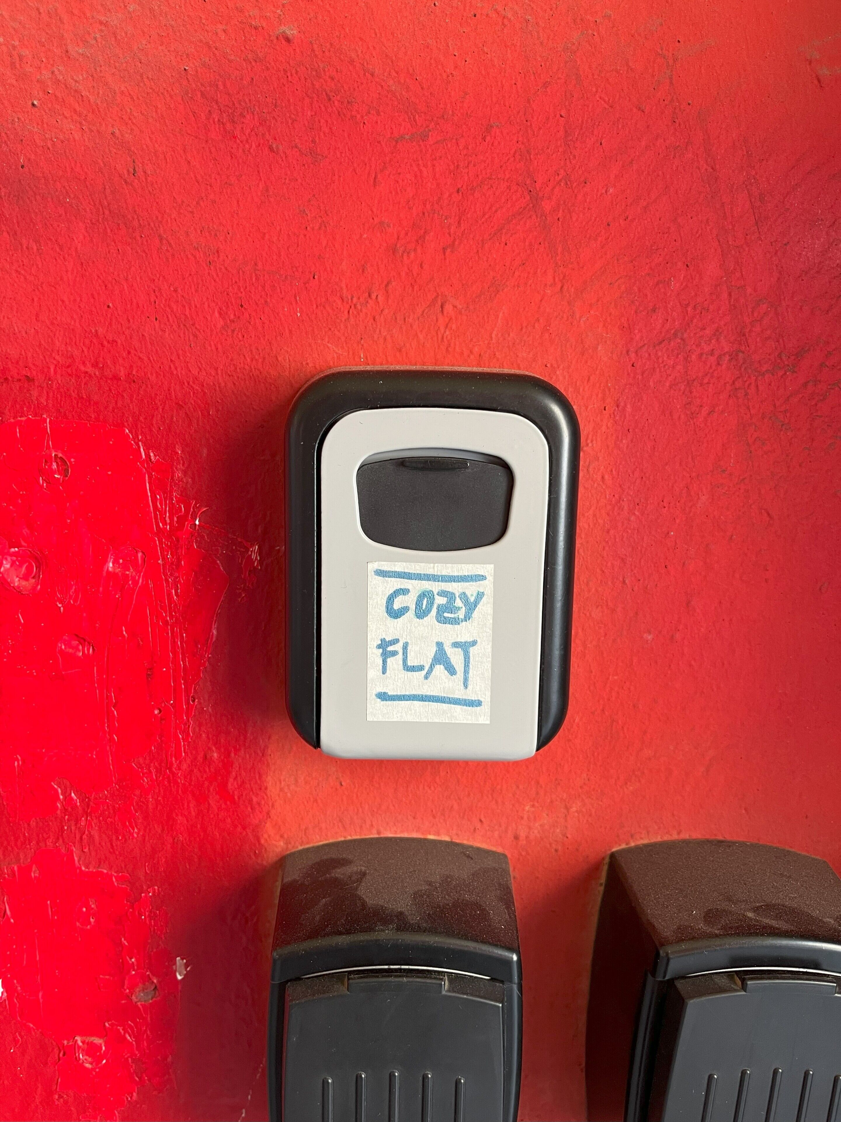A scale with a 'COZY FLAT' label on a red wall.