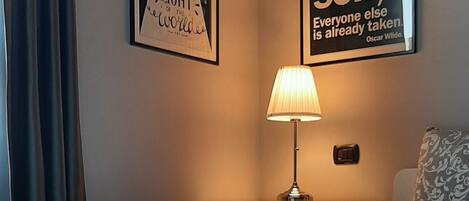 A neatly made bed with a patterned bedspread, a bedside lamp, and two motivational posters on the wall.