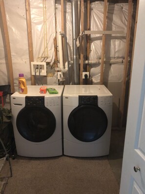 A laundry room with two front-loading washing machines, a utility sink, and a power outlet. - Spacious Single Family Home Near Water, Recreational Areas/Parks, and Shopping.. (New Castle)