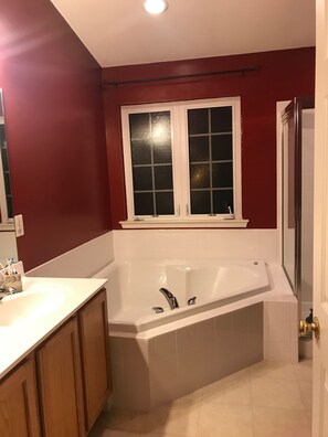 A bathroom with a bathtub, a window, and wooden cabinets.