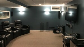 Une salle de cinéma maison dotée d’un espace de sièges incurvé, d’un grand téléviseur à écran plat et d’un sol recouvert de moquette.