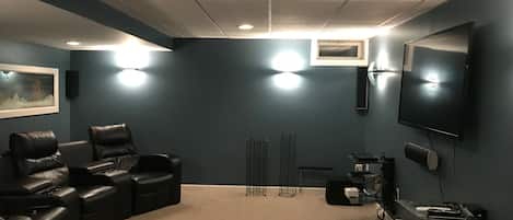 A home theater room with a curved seating area, a large flat-screen TV, and a carpeted floor.