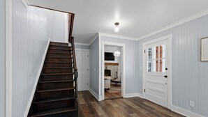 A staircase leading to a room with a fireplace, a door with a window, and a chandelier. - 1900 Farmhouse with Luxury Spa Bath, 2 Master Bedrooms, Historic Home (Whitwell)