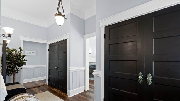 A hallway with dark wooden doors, a white column, and a light fixture. - 1900 Farmhouse with Luxury Spa Bath, 2 Master Bedrooms, Historic Home (Whitwell)
