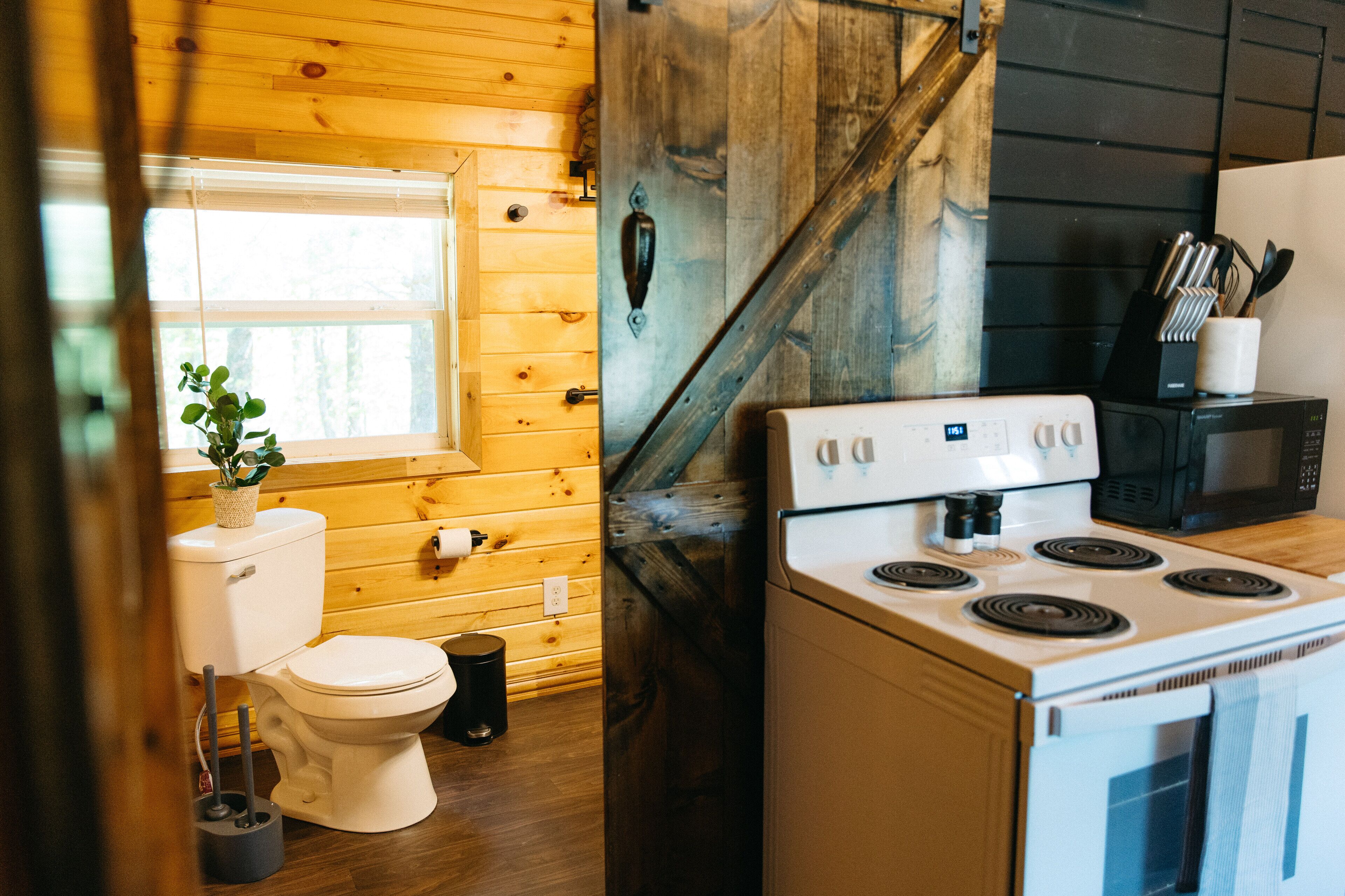 Une cuisine de taille réduite, équipée d’une cuisinière, d’un four à micro-ondes et dotée de murs en bois.