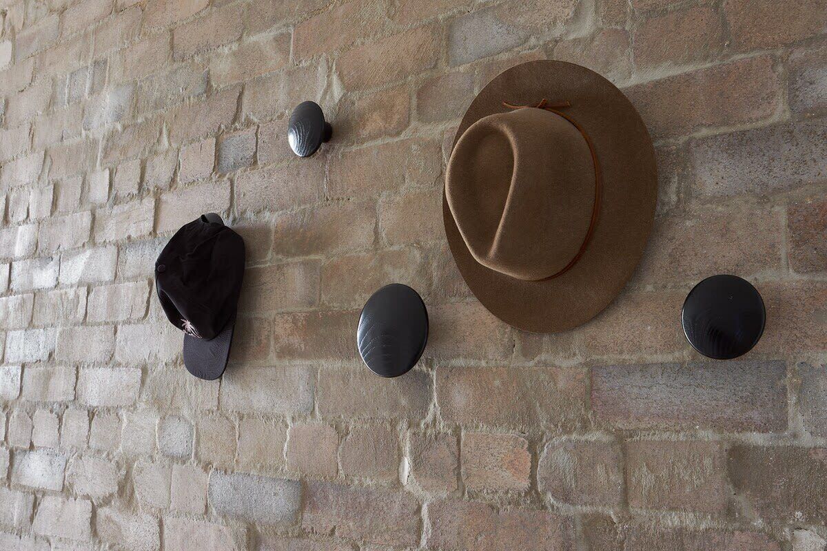 Pared de ladrillo con un sombrero y dos objetos redondos montados.