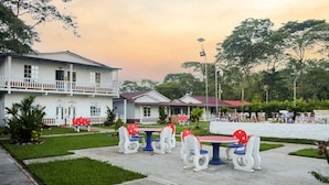 A building with a white exterior and a balcony, surrounded by green lawns and trees. - Hotel Cabañas American Dream (Restrepo)
