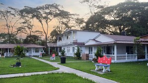 A two-story house with a balcony, surrounded by a well-maintained lawn and trees. - Hotel Cabañas American Dream (Restrepo)