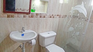 Un baño con lavamanos, inodoro y cabina de ducha de vidrio.