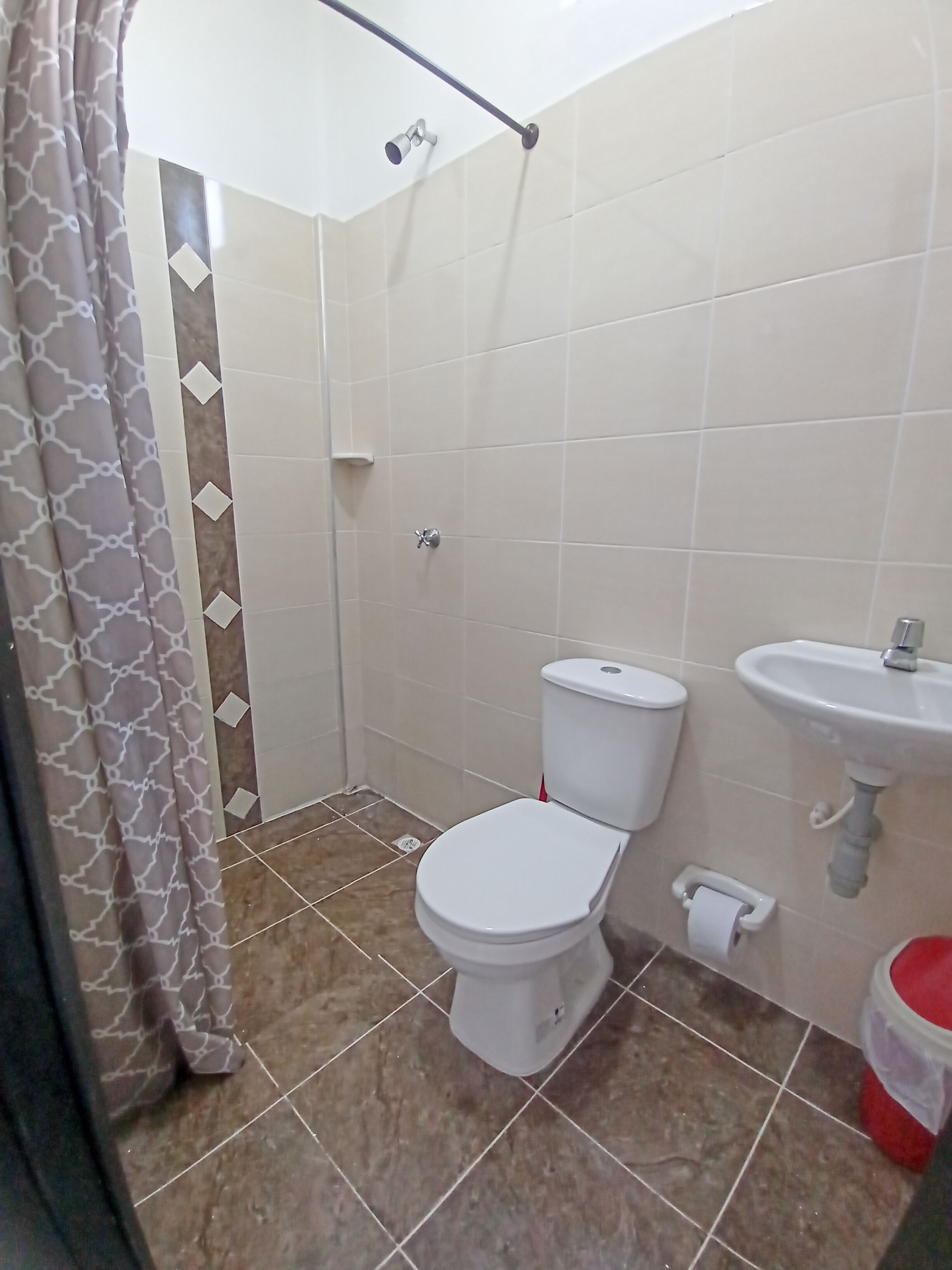 Et badeværelse med toilet, bruser og vask.
