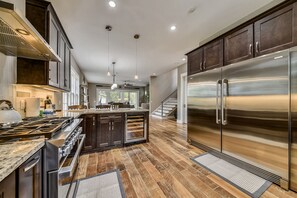 A modern kitchen with a large island, stainless steel appliances, and a wooden floor.