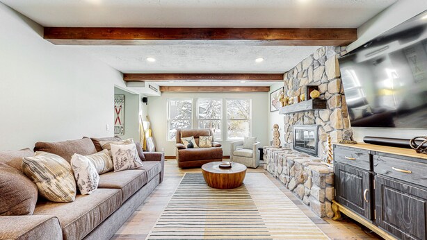 A spacious living room with a stone fireplace, a large TV, and a cozy sofa set. - Summer in Park City, Dog Friendly, Game Room, Hot Tub, Grill, Playground (Park City)