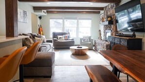 A spacious living room with a large TV, comfortable seating, and a stone accent wall. - Summer in Park City, Dog Friendly, Game Room, Hot Tub, Grill, Playground (Park City)